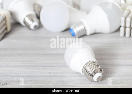 Una lampada a LED bianca da primo piano e lampade a risparmio energetico su una tavola di legno grigia Foto Stock