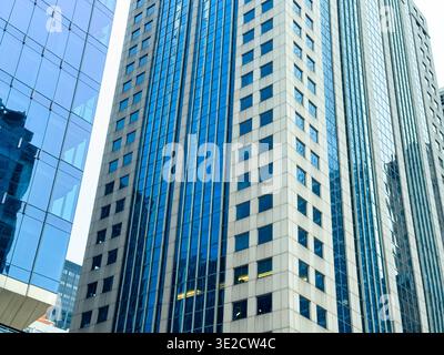 Diversi edifici di uffici con facciate di vetro raggiungono il cielo in un'area urbana sotto la luce del giorno. Foto Stock