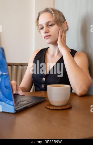 Donna d'affari informale che utilizza un notebook e lavora in freelance in un ambiente luminoso Foto Stock