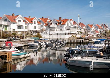 Panorama del porto di Åstol a Bohuslän, costa occidentale della Svezia, con case bianche, piccole barche e riflessi di acque calme Foto Stock