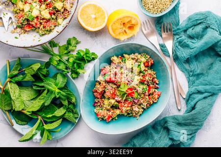 Insalata di couscous colorata con pomodori e cetrioli in un recipiente rustico, guarnita con menta fresca Foto Stock