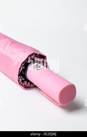 Ombrello rosa compatto con tessuto liscio e manico rosa con pulsanti ergonomici per l'apertura e la chiusura. Corpo metallico e materiale impermeabile ensu Foto Stock