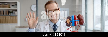 Ritratto di uomo caucasico di mezza età Urologo che sventola in Ufficio medico Foto Stock