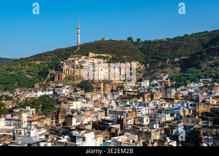 L'ampio Garh Palace di Bundi sorge sopra i fitti edifici della città, con l'alta torre della televisione visibile sulla collina in lontananza. Foto Stock