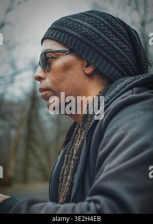 Un uomo con cappello a maglia e occhiali da sole con dreadlock Foto Stock