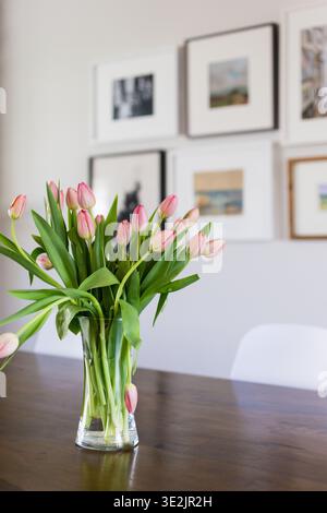 Tulipani rosa in vaso di vetro su tavolo da pranzo in legno Foto Stock