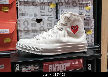 Penang, Malesia - 16 ottobre 2025: Un paio di sneakers alte Converse bianche è esposto su uno sfondo di calzaturifici brandizzati, con un'attenzione particolare Foto Stock