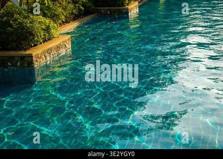 Superficie limpida dell'acqua della piscina con riflessi vicino al bordo, ambiente tropicale. Concetto: Manutenzione della piscina e pulizia dell'acqua Foto Stock