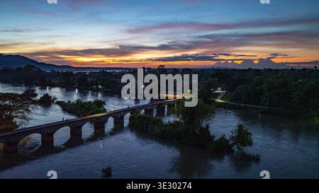 Una vista aerea panoramica del ponte rosso che attraversa il fiume Mekong vicino alla cascata li Phi, nota anche come Tad Somphamit al tramonto. Il tranquillo fiume atterra Foto Stock