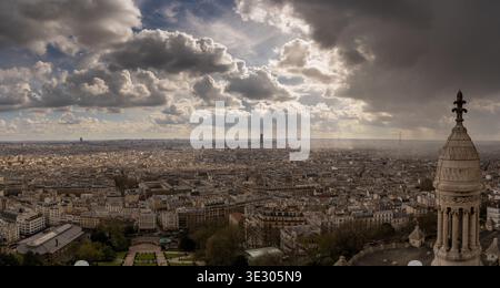 Vista panoramica dello skyline di Parigi da Montmartre vicino al Sacré-Cœur, con spettacolari nuvole e raggi del sole. Foto Stock
