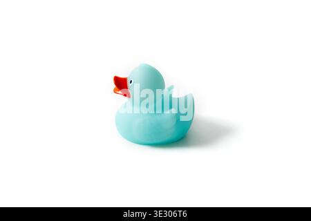 Vista laterale di un simpatico giocattolo di anatra in gomma azzurra isolato su sfondo bianco con ombre morbide. Immagine del profilo di un anatra di plastica blu con becco arancione Foto Stock