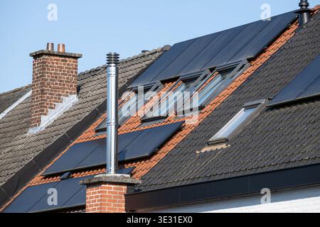 Pannelli solari installati su un tetto recentemente rinnovato con camino, riflettendo le attuali tendenze in materia di efficienza energetica, isolamento e sostenibilità ambientale Foto Stock