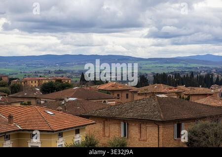 Tranquilla scena rurale. Tranquillo paesaggio toscano con colline e tetti. Pittoresco paesaggio del villaggio con tetti in terracotta e terreno rotabile Foto Stock