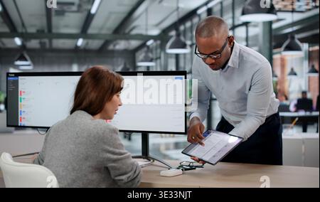 Young Woman and Man utilizzano strumenti software, controllando attentamente i problemi di sistema. Due professionisti IT monitorano i tempi di inattività dei siti Web Foto Stock