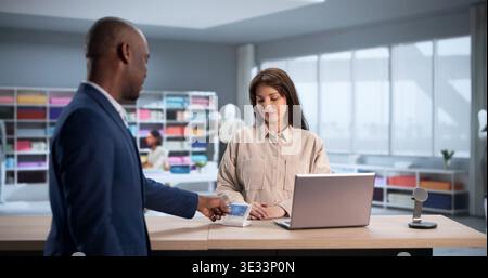 Young Man sceglie con cura il tessuto pagando su misura con carta di credito Foto Stock