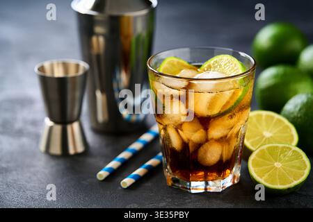 Cocktail cuba libre con rum marrone, cola e lime in bicchieri su un tavolo scuro. Foto Stock