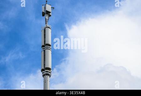 Primo piano del montante di telefonia mobile 5G con antenne contro il cielo blu, moderne infrastrutture di telecomunicazione e tecnologia di rete wireless. Foto Stock