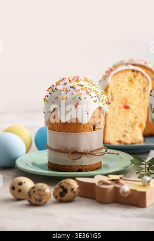 Piatti con dolci torte di Pasqua, uova diverse e coniglietto di legno sul tavolo grigio Foto Stock