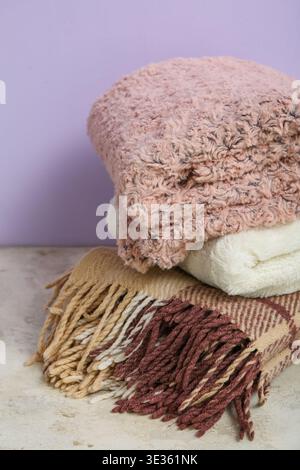 Nuove morbide coperte piegate sul tavolo nuovo muro viola Foto Stock