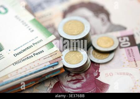 Banconote messicane in peso e monete centavo si accumulano sul tavolo. Monete messicane sulle banconote in valuta MXN da vicino. Concetto di affari, tasse e banche in Messico Foto Stock