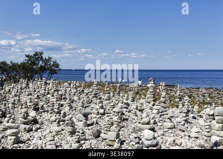 Campo di macerie, spiaggia rocciosa, costa con sentiero escursionistico sull'isola di Stora Grunddet, escursionisti, mucchi di pietre, uomini di pietra, Mar Baltico, Oeland, Kalmar laen Foto Stock