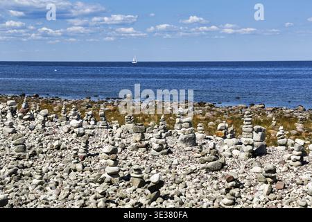 Campo di macerie, spiaggia rocciosa, costa con sentiero escursionistico sull'isola di Stora Grunddet, barca a vela all'orizzonte, mucchio di pietra, uomini di pietra, Mar Baltico, Oeland, K Foto Stock
