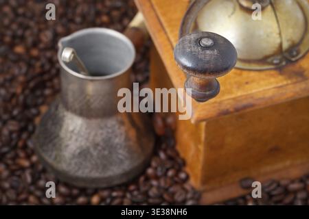 Macinacaffè manuale retrò e pentola in rame su molti chicchi di caffè tostati Foto Stock