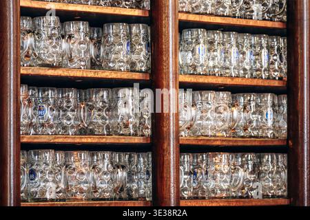 Monaco di Baviera, Germania - 15 aprile 2025: Tazze da birra tradizionali Hofbrauhaus esposte su scaffali in legno all'interno della storica birreria Hofbrauhaus di Monaco, G. Foto Stock