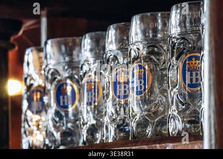 Monaco di Baviera, Germania - 15 aprile 2025: Tazze da birra tradizionali Hofbrauhaus esposte su scaffali in legno all'interno della storica birreria Hofbrauhaus di Monaco, G. Foto Stock