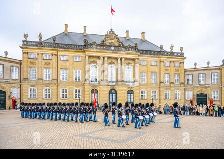 DANIMARCA, COPENHAGE - 12 APRILE 2025: Le guardie eseguono la cerimonia del cambio della guardia al Palazzo di Amalienborg a Copenaghen. Questo evento include una marcia e un'esibizione di batteria davanti ai visitatori. Foto Stock