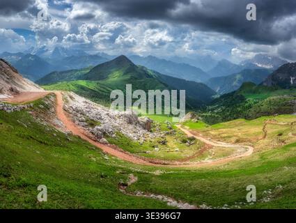 Tortuosa strada di montagna in una vibrante valle verde, montagne alpine Foto Stock