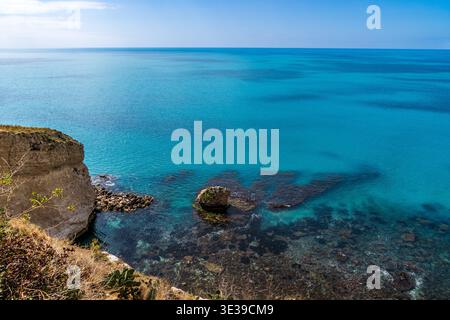 Vista ad alto angolo della costa di Sciacca in Sicilia. L'immagine presenta una scogliera calcarea che si affaccia su un mare turchese trasparente con fondali rocciosi visibili Foto Stock