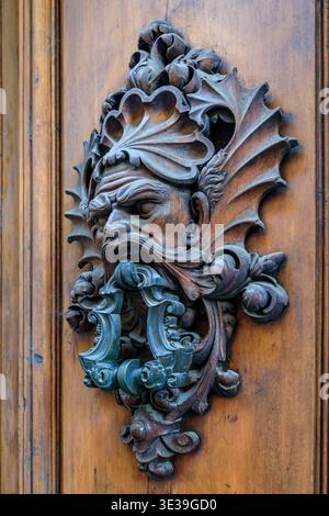 Porta in metallo in stile rinascimentale antico decorato a forma di grottesco maschera con ali intricate su una porta in legno intemprata a Firenze, Italia Foto Stock