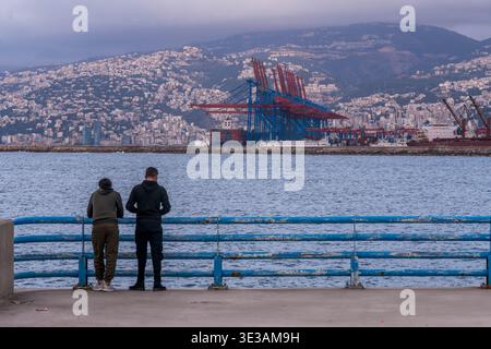 Passeggiata mediterranea lungo la Beirut Corniche con lontane gru portuali e colline del Monte Libano sullo sfondo, Beirut. Foto Stock