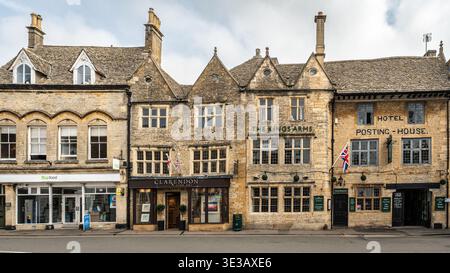 Vista panoramica con tradizionali edifici in pietra del Cotswold, tra cui il Kings Arms Hotel, Cotswolds, Inghilterra Foto Stock