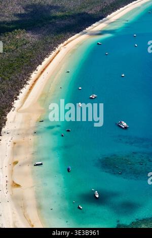 Una vista aerea di Whitehaven Beach nelle Whitsundays, Australia, che mostra le sue incontaminate sabbie bianche e le acque turchesi punteggiate di barche e nuotatori che si godono una giornata di sole. Foto Stock