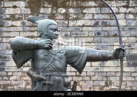 La statua di Robin Hood si erge orgogliosamente su Castle Road a Nottingham, in Inghilterra, puntando la freccia verso la storica portineria del castello di Nottingham. Foto Stock
