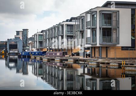 Edimburgo, Scozia - 10 agosto 2012: Moderni edifici abitativi e barche a remi ormeggiate lungo l'Union Canal vicino al Leamington Lift Bridge, riflessi Foto Stock