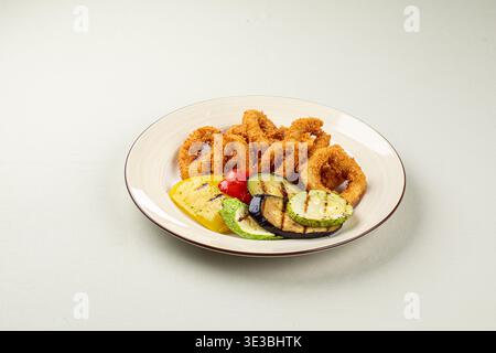 Anelli di cipolla fritti croccanti con verdure grigliate Foto Stock