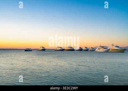 Una vista panoramica di diversi yacht ancorati nel calmo Mar Rosso all'alba a Hurghada, in Egitto, durante una tranquilla mattinata di primavera. Foto Stock