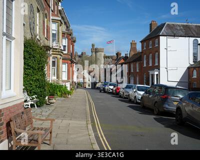 Una vista del Castello di Arundel da Maltravers Street che mostra case residenziali e strade in primo piano. In una soleggiata giornata di cielo azzurro con Union Jack in volo. Foto Stock