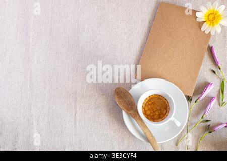 Vista dall'alto minimalista con fiori e una tazza di caffè da un lato. Ampio spazio per testo, ideale per pubblicità e campagne stagionali Foto Stock
