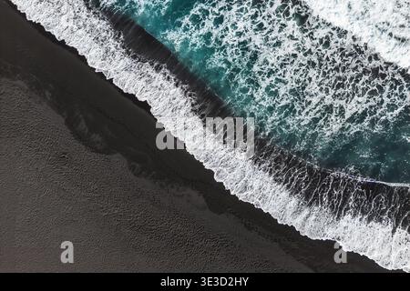 Pile astratte di onde sulla spiaggia di sabbia nera, vista dall'alto verso il basso. Foto Stock