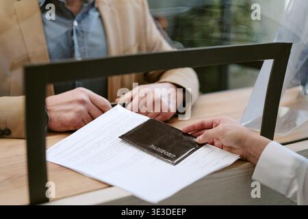 Uomo di mezza età che invia passaporto e documenti alla filiale della banca Foto Stock