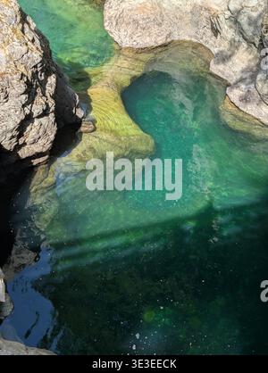 Fiume color smeraldo naturale tra la foresta delle montagne dell'isola di Vancouver in estate su una piccola e soleggiata cascata Qualicum, BC, Canada Foto Stock