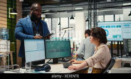Uomini e donne diversi che si salutano a vicenda con un pugno di saluto nello spazio aziendale, gli amici di ufficio salutano prima di iniziare a lavorare alle attività organizzative quotidiane. Multinazionale. Foto Stock