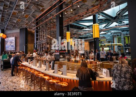 Milano, Italia - 9 marzo 24: Ampia vista del lungo bar in marmo con sgabelli e attrezzature da caffè all'interno della Starbucks Reserve Roastery di Milano, Italia. Foto Stock