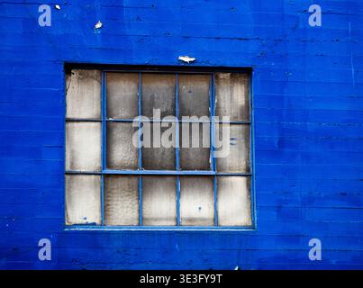 pareti di colore blu con finestre sbiadite in un vecchio edificio industriale in mattoni Foto Stock
