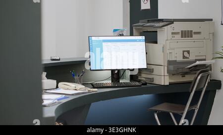 Reception contatore in centro di salute per effettuare appuntamenti su computer, dando supporto medico ai pazienti. Banco di registrazione dell'ospedale vuoto con documenti di report e moduli di controllo. Scatto manuale. Foto Stock