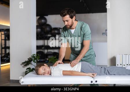 Fisioterapista che esegue un massaggio schiena manuale per bambini Foto Stock